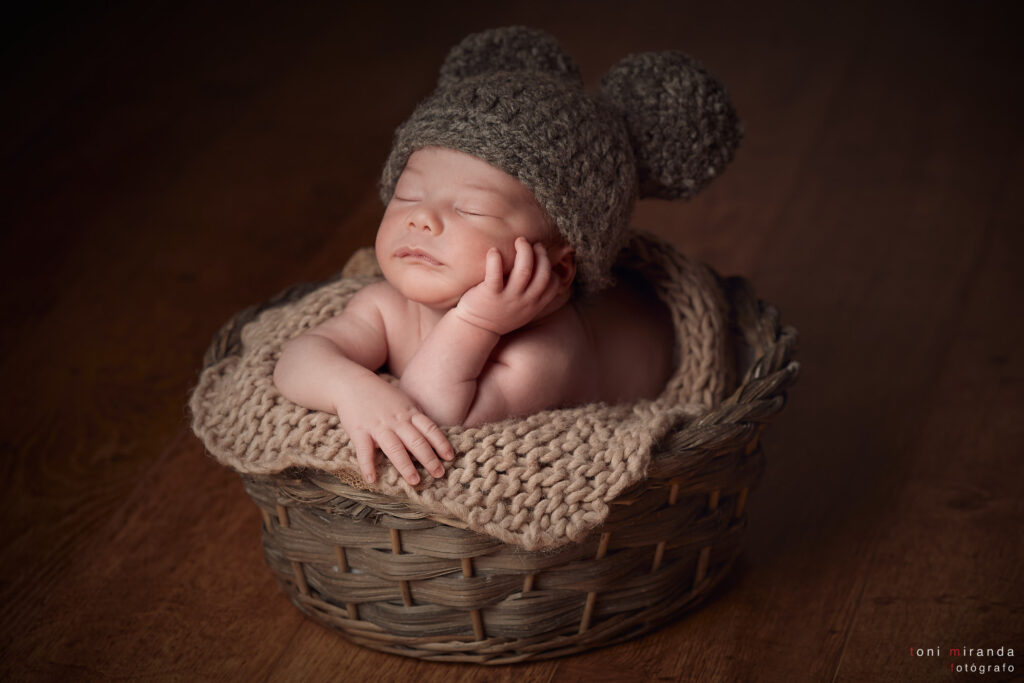 bebe en cesta durmiendo con gorro de bolas